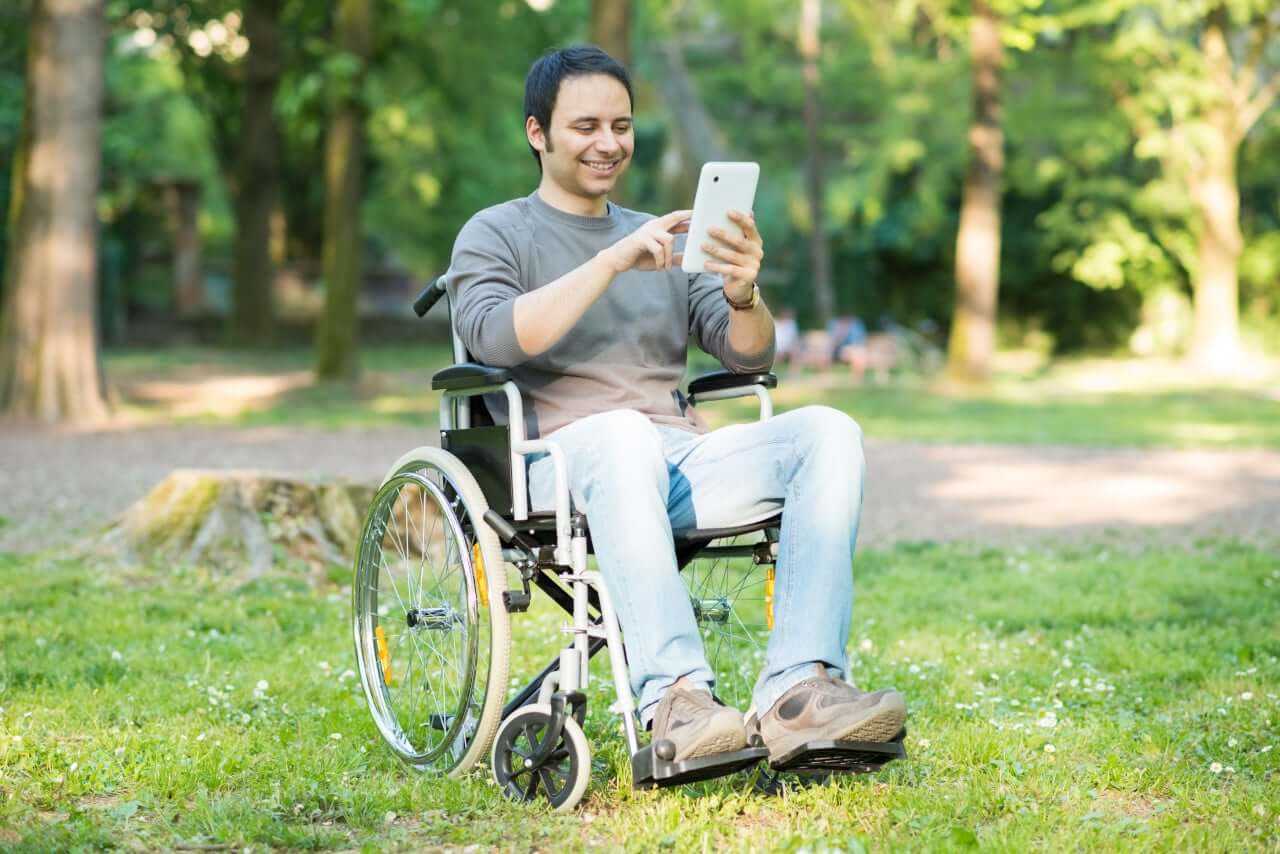 Man in wheelchair tapping on a tablet computer